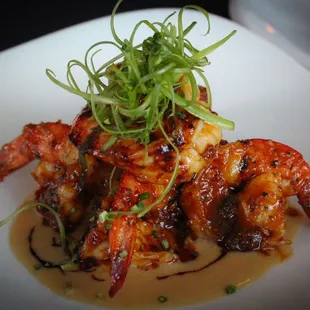 a plate of shrimp with sauce and garnish