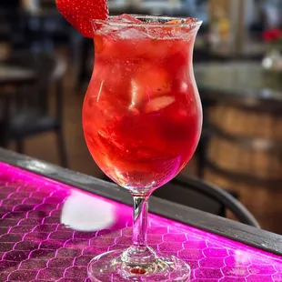 a red drink with a strawberry garnish
