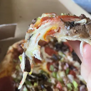 a hand holding a slice of pizza