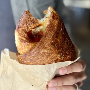 a person holding a croissant sandwich