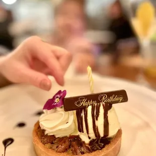 a person placing a candle on a dessert