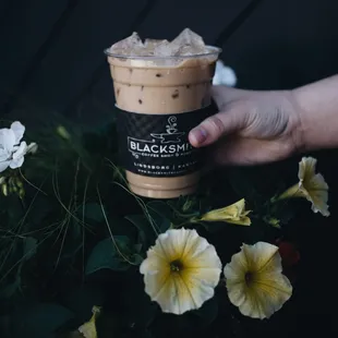 a hand holding a cup of iced coffee
