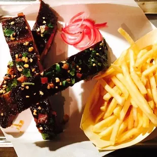 a tray of food with french fries and ribs
