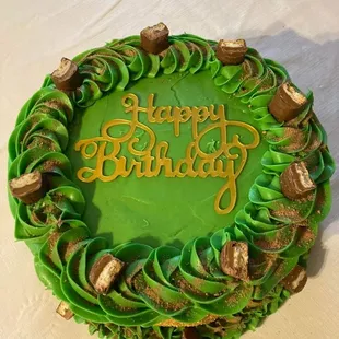 Two Layered 10" caramel vanilla cake layered with crushed Twix bars iced with homemade buttercream frosting garnished with Twix bars