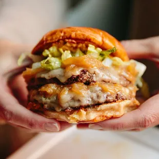 a hand holding a cheeseburger