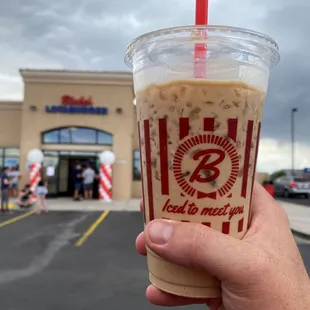 a hand holding a cup of iced coffee
