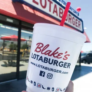 a hand holding a cup with a straw