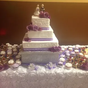 Beautiful wedding cake with cupcakes and flan pieces all around it.