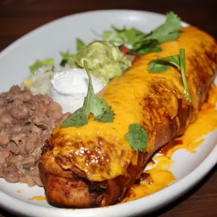 The Short Rib Machaca Chimichanga is made with cheese, guacamole, sour cream, pico de gallo, rice &amp; beans.