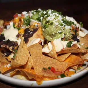 The Nachos Con Queso Blanco are made with avocado, crema fresca, black bean, pico de gallo with the addition of Red Chile Chicken.