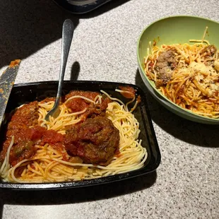 Spaghetti with one meatball on the left. On the right, in the bowl, is spaghetti with half of the sauce and a cut up meatball.