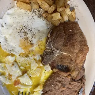 Pork Chop, eggs refried beans and potato plate.