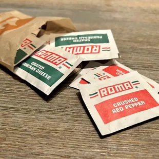 Packets of crushed red pepper flakes and grated parmesan cheese.