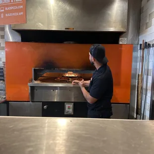 The worker being cool cooking the pizza