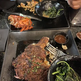 Half eaten 22oz steak over potatoes and side of spinach. Remains  of fried lobster and jambalaya rice