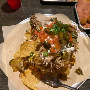 a plate of nachos with a side of fried chicken