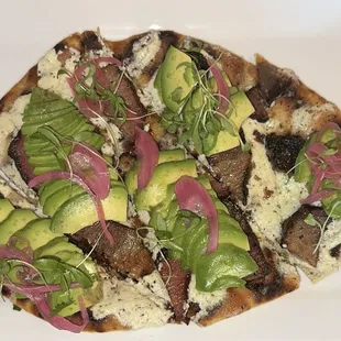 Flatbread with brisket, feta, avocado, and pickled onions.