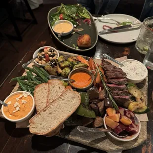 Harvest board with steak for 1. There&apos;s also one of three crabcakes left on that top plate.