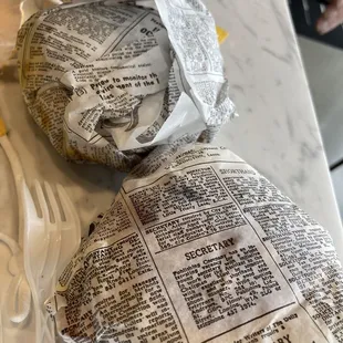 a sandwich wrapped in newspaper
