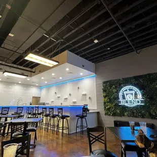 a restaurant with tables and stools in front of a bar
