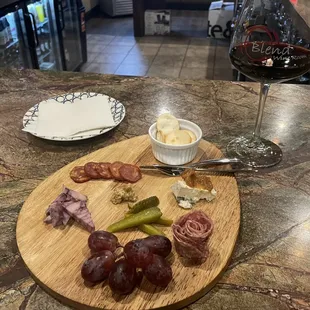 a plate of meat and cheese with a glass of wine