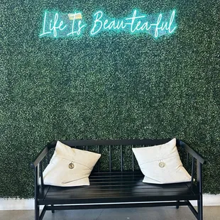 a bench with pillows and a neon sign that says life is beautiful