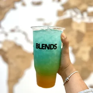 a person holding a drink in front of a world map