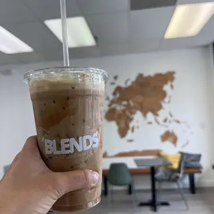 a hand holding a cup of iced coffee