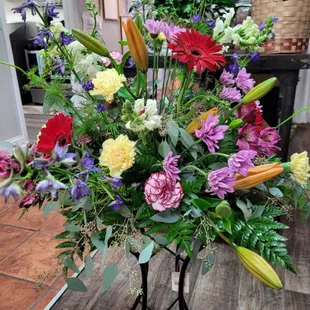 Lily's, gerbera daisy's, roses, delphinium, arranged in bird bath. The family will have something to place in their garden.