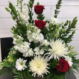 White stock, spider mums, daisy's assorted greenery, red roses arranged in a classy design.