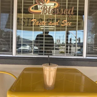 Small yellow table holding my coffee and below window sign.