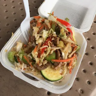 a takeout container with a salad in it