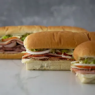 three sub sandwiches on a table