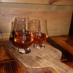 three glasses of brandy on a wooden tray