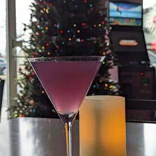 a purple cocktail in front of a christmas tree