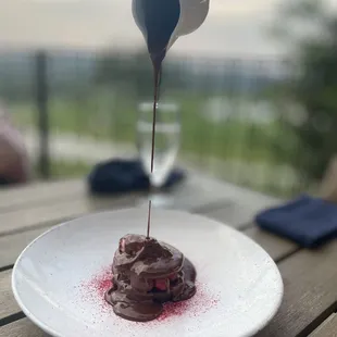 a chocolate dessert being drizzled with chocolate