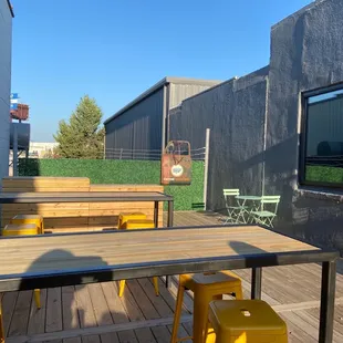 a patio with tables and yellow stools