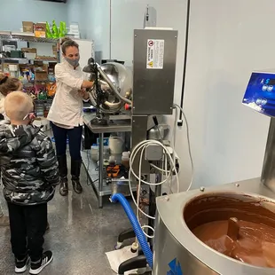 The owner taking a group of kiddos in the back and explaining the chocolate making process.