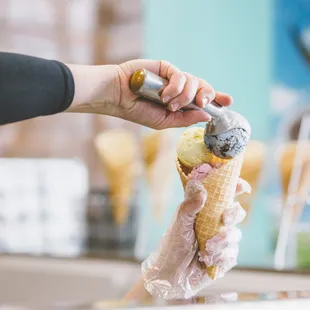 a person scooping ice cream into a cone