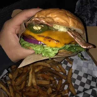 a hand holding a sandwich and french fries