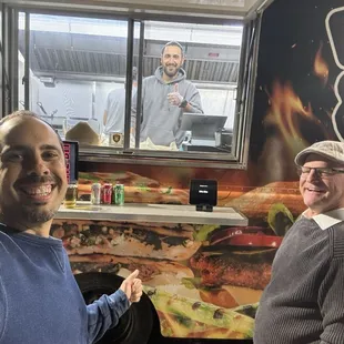 two men standing in front of a food truck