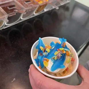 a hand holding a bowl of ice cream