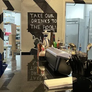 a bar counter with a sign that says take our drinks to the pool