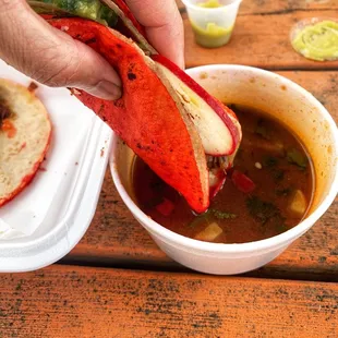 a person dipping something into a bowl of soup