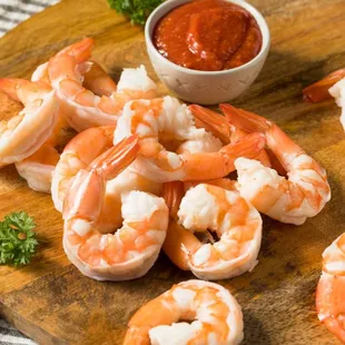 shrimp on a cutting board with a bowl of ketchup