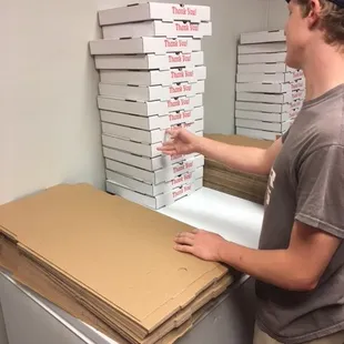 a man standing in front of a stack of pizza boxes