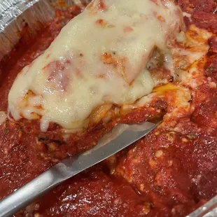 A piece of delicious lasagna with plenty of sauce