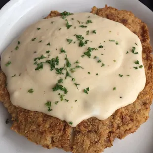 a fried chicken breast covered in a creamy sauce