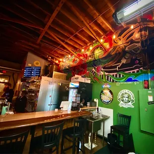 a bar with a green wall and wooden ceiling