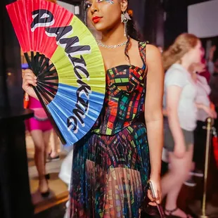 a woman in a colorful dress holding a fan
